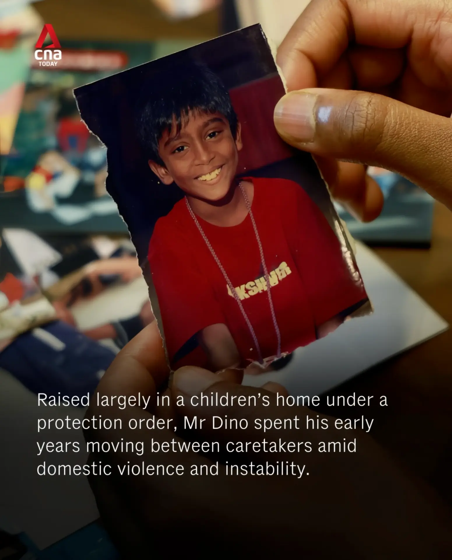 A worn childhood photograph of Dino in a red shirt held in hand